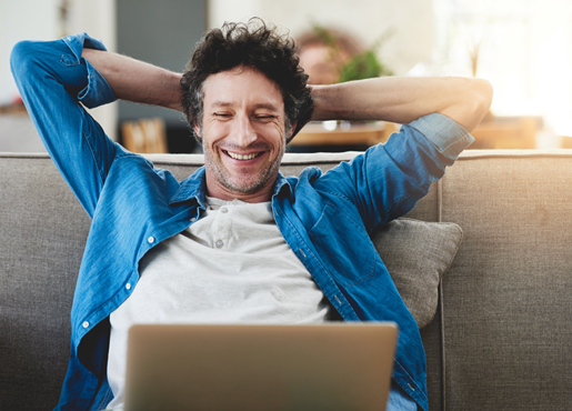 Happy man relaxed on couch with laptop