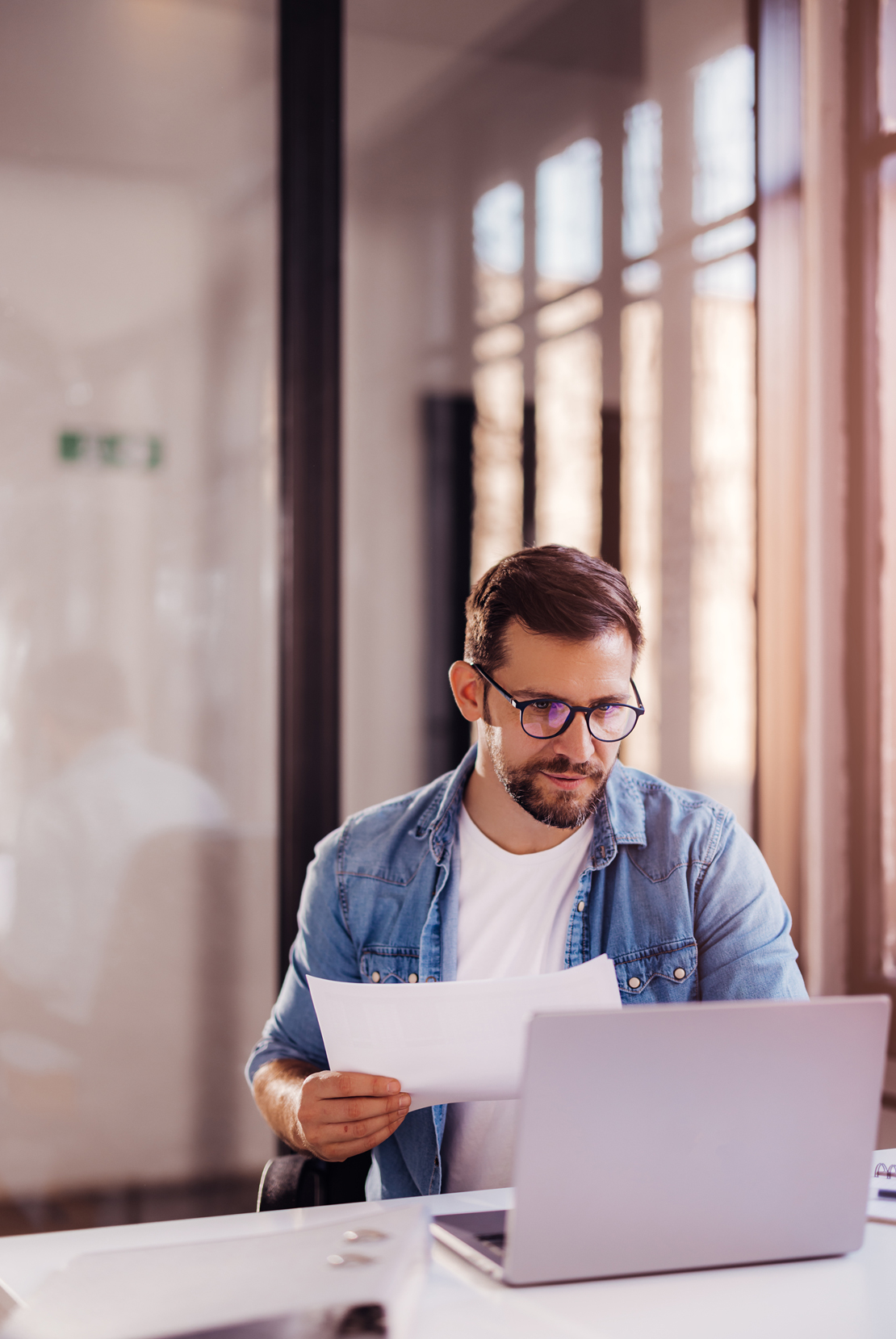 Man in casual work wear at desk working on laptop