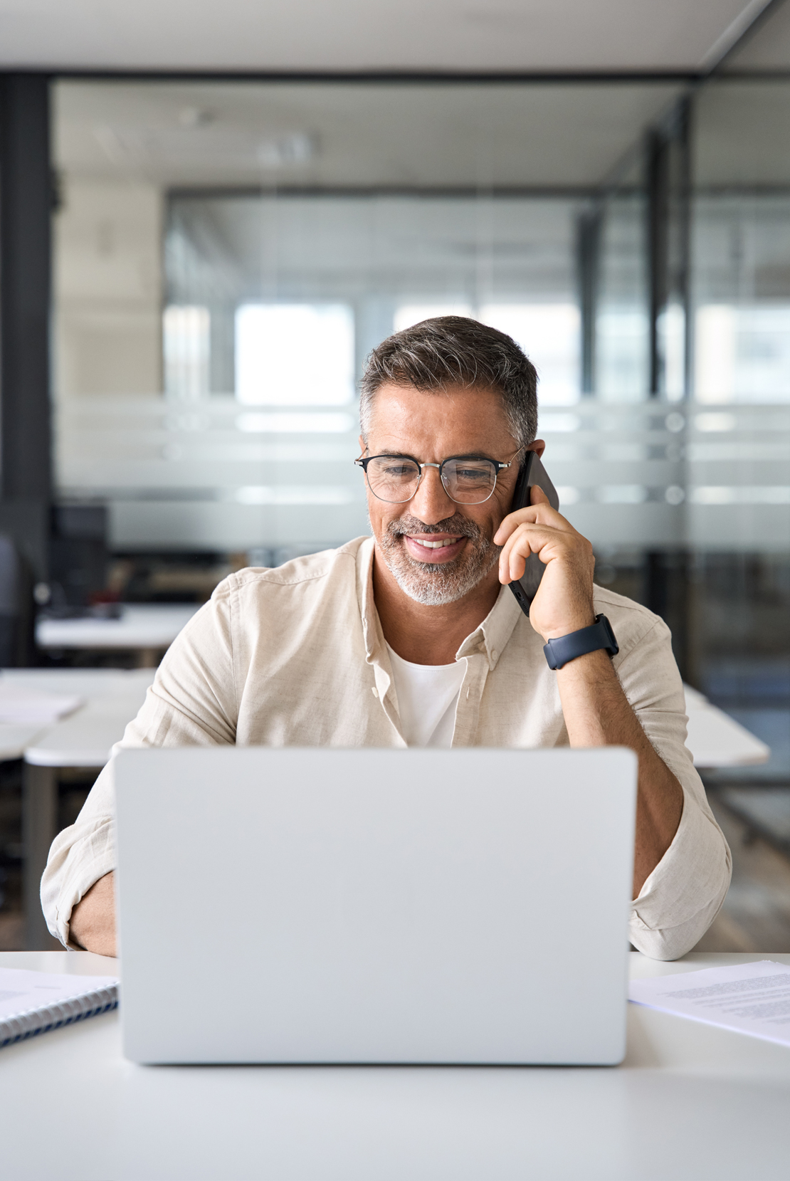 Man on a call at a desk working on laptop